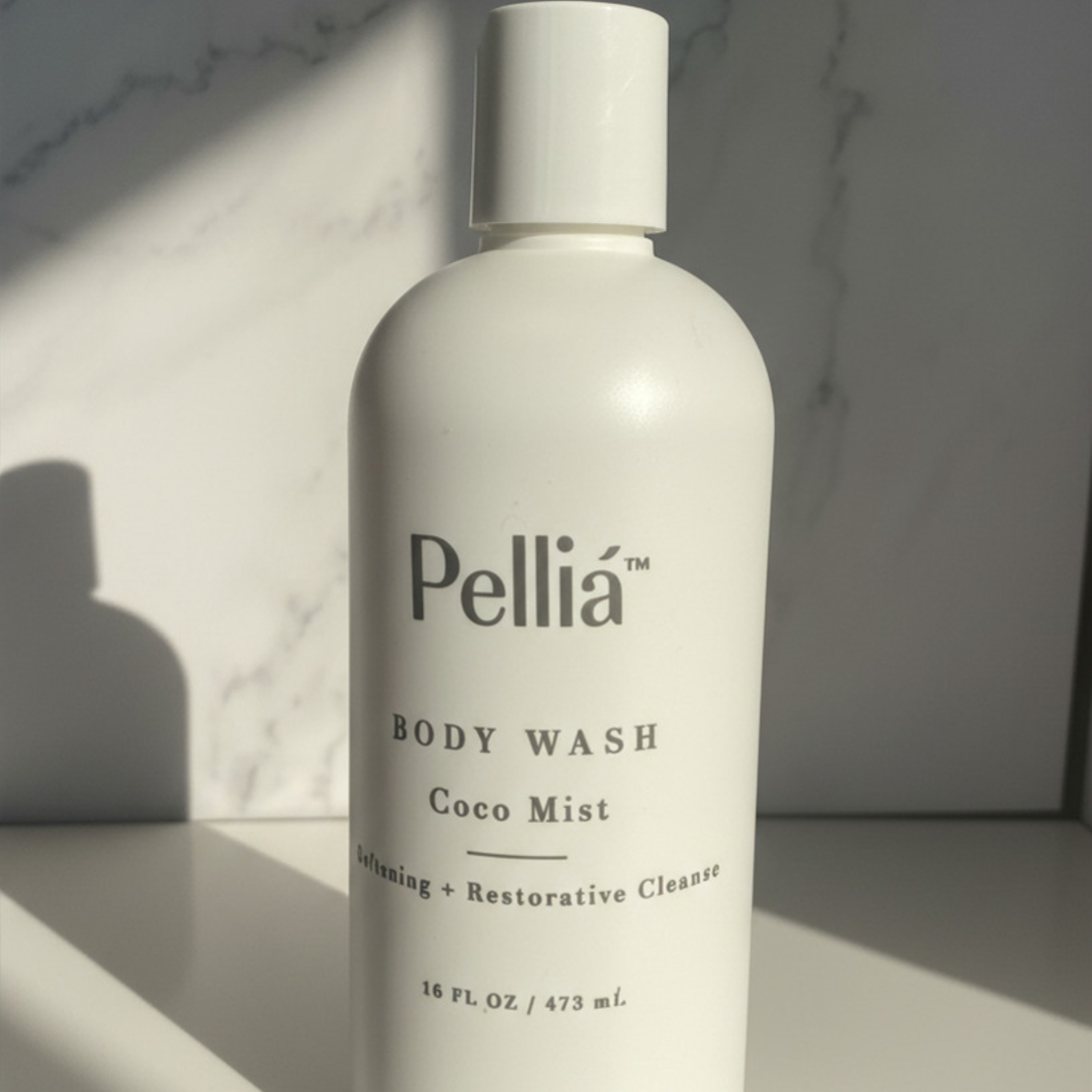 Coco Mist body wash full size on a marble background.